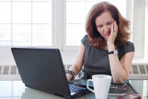 Woman tired drinking coffee and doing work at computer