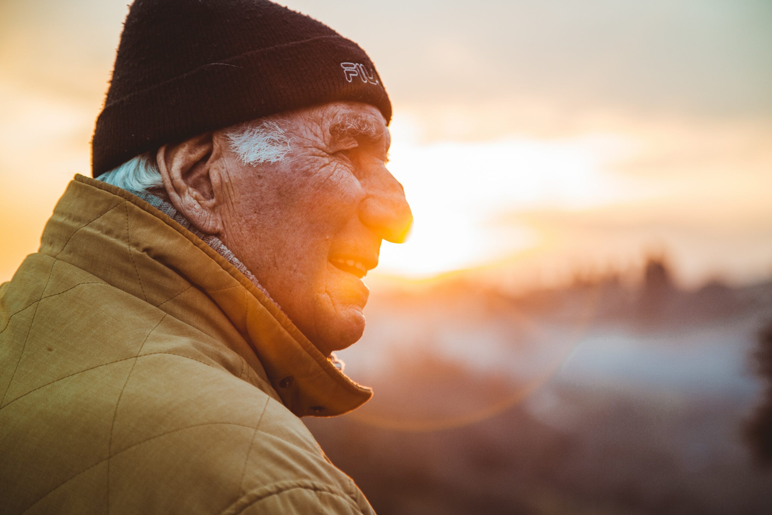 Older man gazes off at sunset with weathered skin